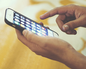 Mãos mexendo em celular ilustra a atualização iOS 14